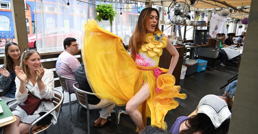 A drag queen in yellow struts in a cafe as part of WorldPride-sponsored drag queen "brunch."