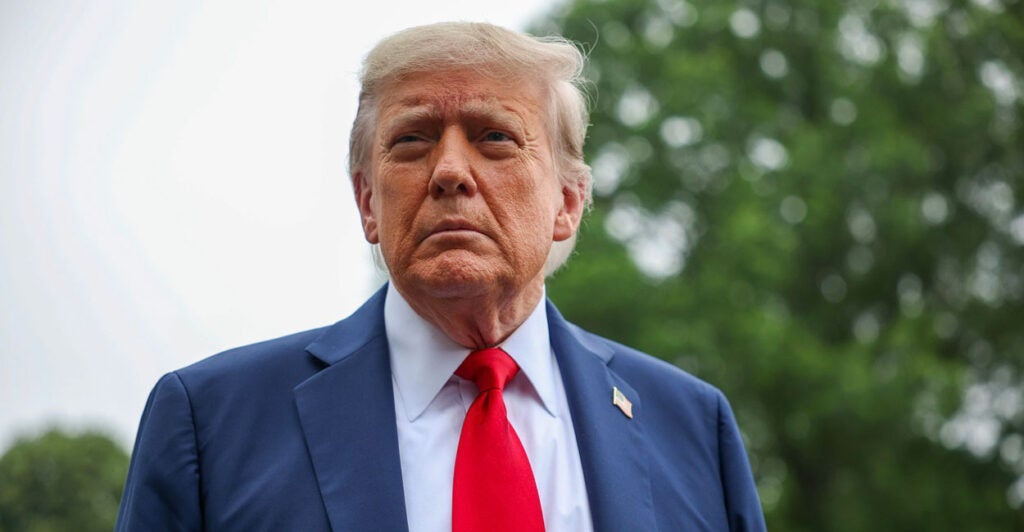 Donald Trump stops to talk to the media and looks to his right.