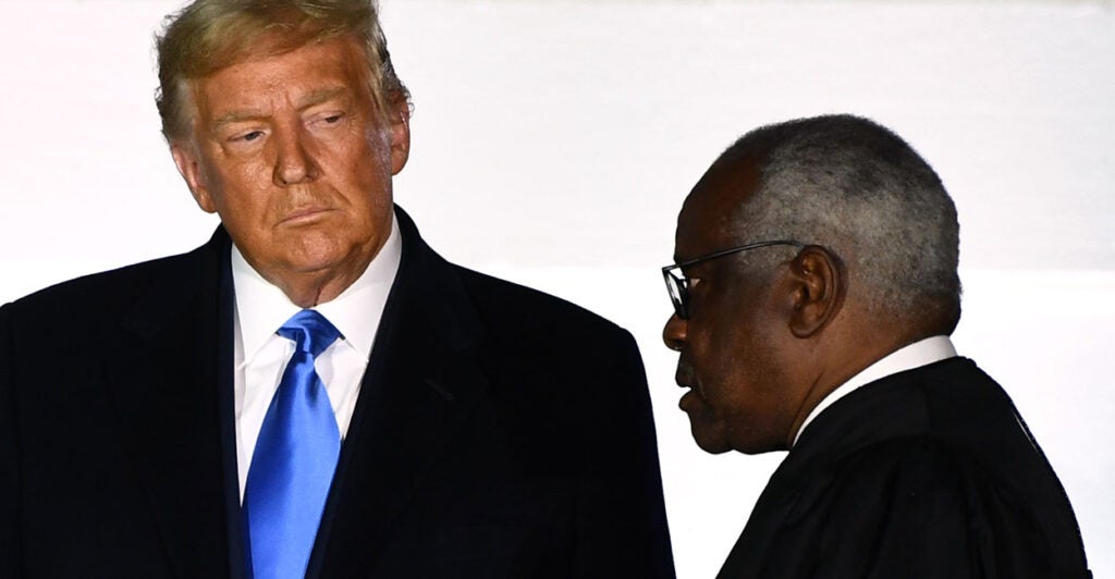 President Donald Trump looks at Supreme Court Justice Clarence Thomas, who is in profile.