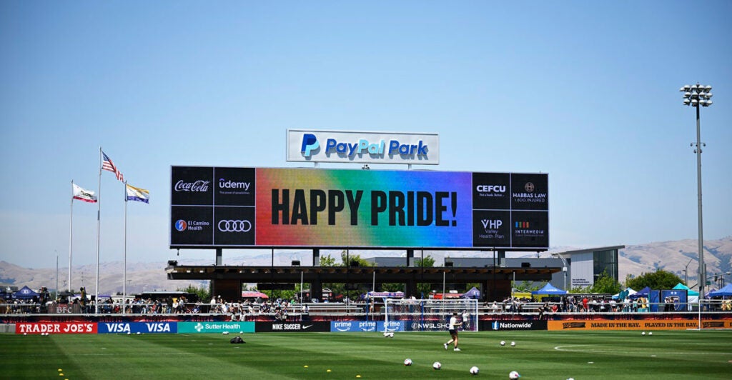 An electronic billboard at a sporting event displays the message "Happy Pride!"
