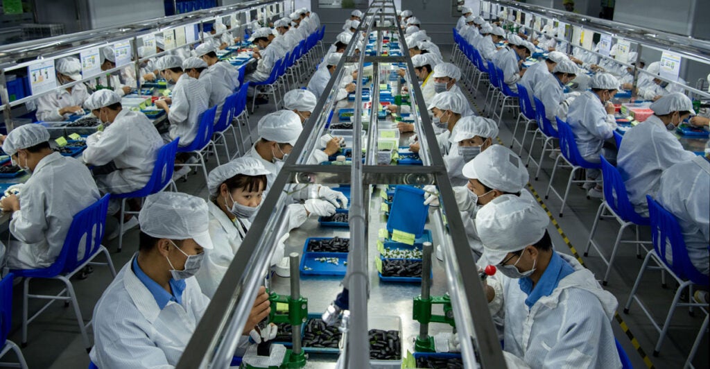 Dozens of workers clad in white frocks and hats work on pods for e-cigarettes at a Chinese factory.