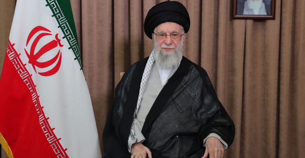 Iranian Ayatollah Ali Khamenei with an Iranian flag as backdrop