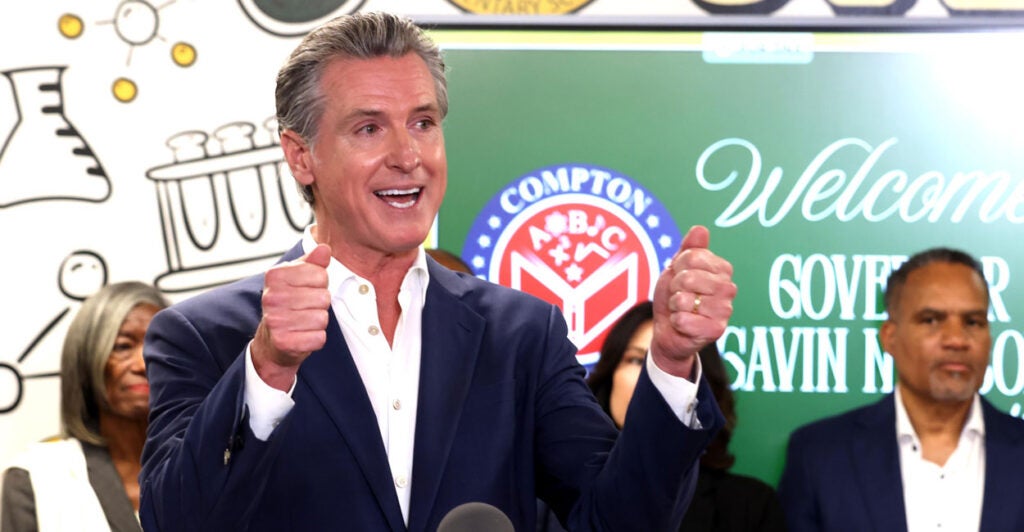 Gavin Newsome offers two thumbs up while at an elementary school.