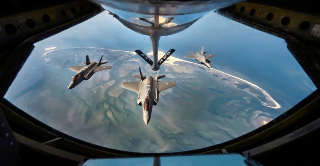 F-35 fighter as seen out of the cargo hold of plane flying above.