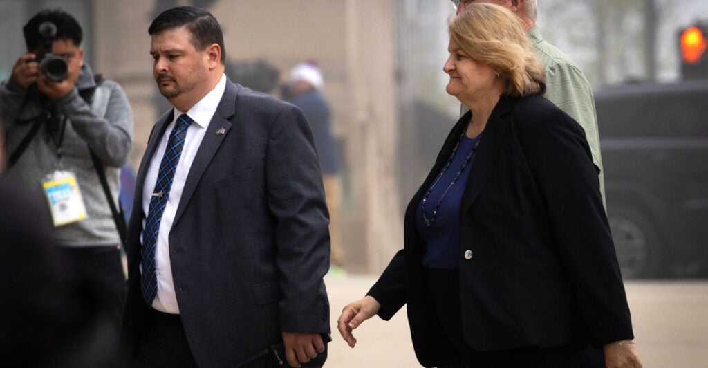 Milwaukee County Circuit Judge Hannah Dugan walks into the Milwaukee Federal Courthouse with suited man at her side.