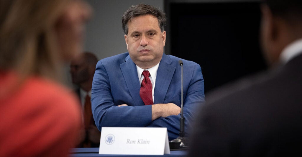 Ron Klain, chief of staff for Joe Biden, sits with arms folded at a meeting, his cheeks puffed out as if letting out a big exhale.
