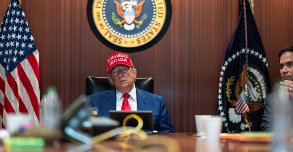 President Trump in a MAGA hat sits at a table in the White House Situation room.