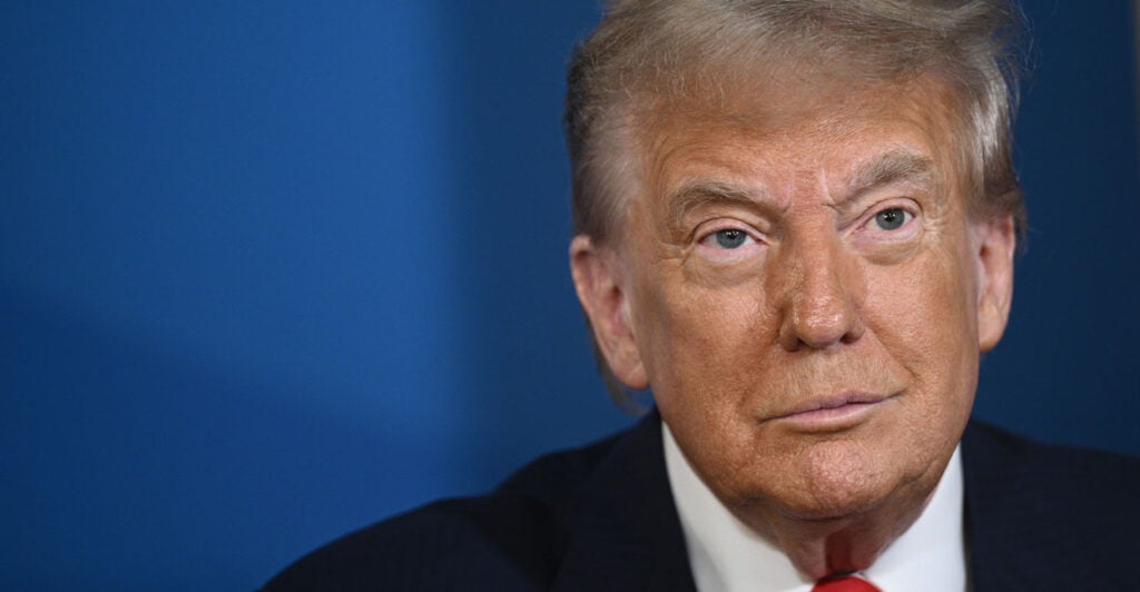 A closeup photo of President Donald Trump shows Trump smiling slightly.