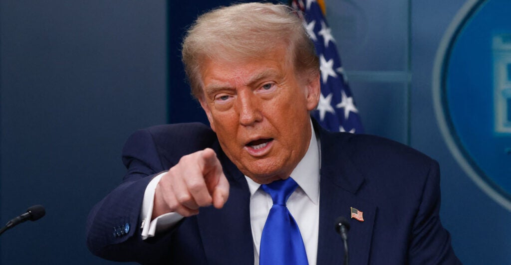 President Donald Trump in a blue suit and tie points during a news conference at the White House.