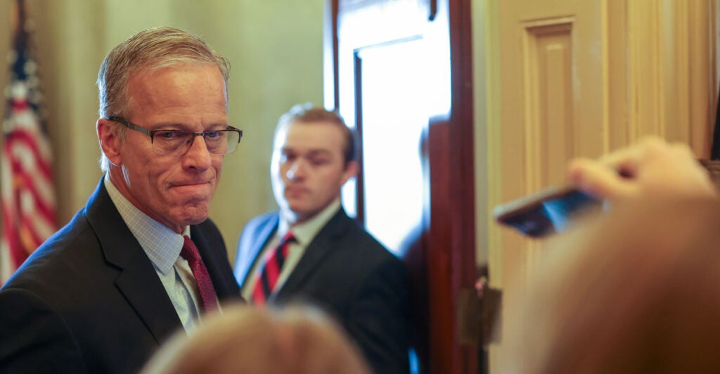 Senate Majority Leader John Thum with lips pursed standing with reporters outside Senate chamber.