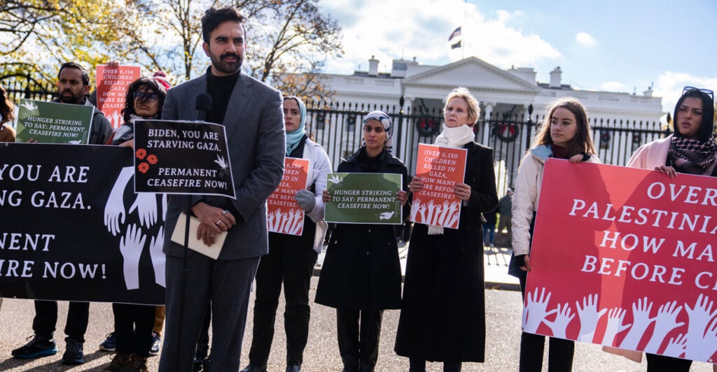 Zohran Mamdani speaking at a 2023 pro-Gaza, anti-Biden protest in front of White House. A group of people are behind him, including actress Cynthia Nixon.