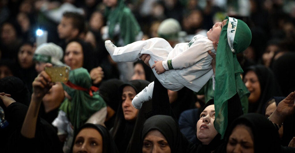 An Iranian woman holds her young child aloft in a crowd in Tehran on Oct. 7, 2016.