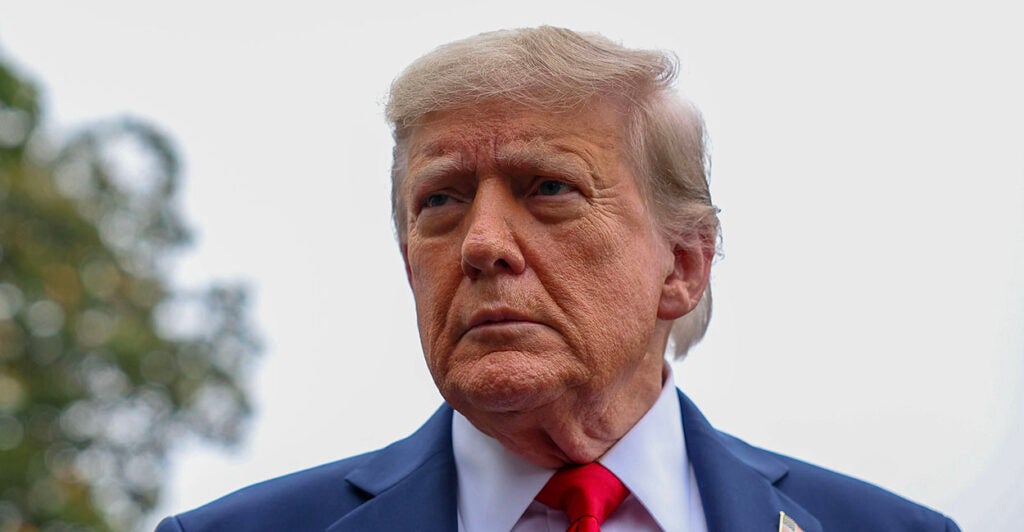 President Donald Trump in a blue suit looks into the distance