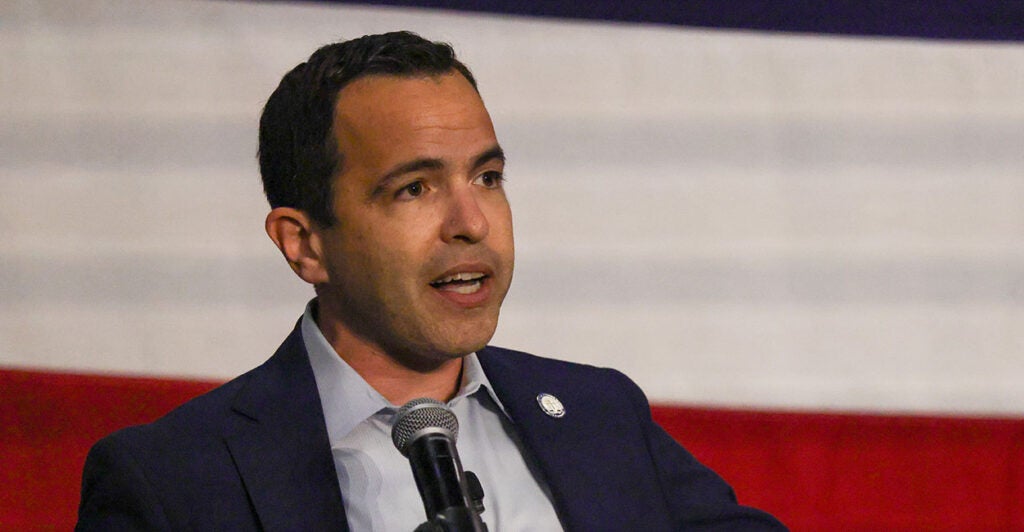 Matt Platkin in a suit in front of a microphone