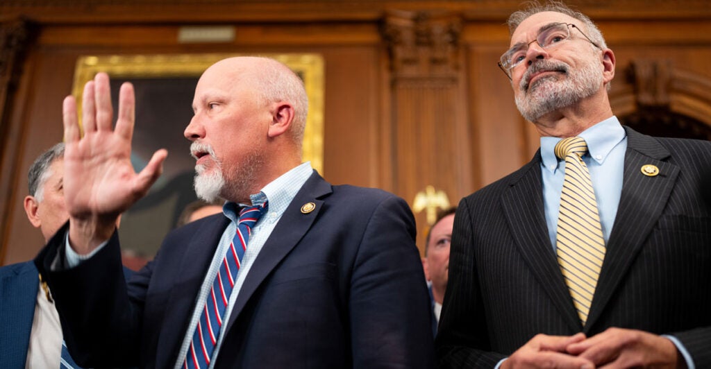 Andy Harris and Chip Roy speak to reporters, with Roy having a hand near his face.