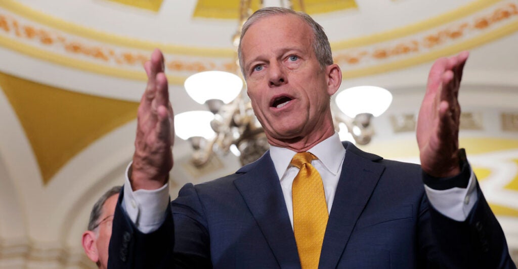 Senate Majority Leader John Thune gestures with both hands.