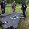 Ukrainian explosives experts and police officers examine parts of a Shahed 136 military drone.