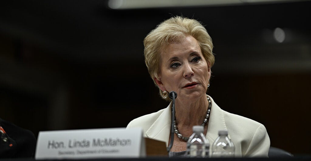 Education Secretary Linda McMahon in a white suit sits at a table.