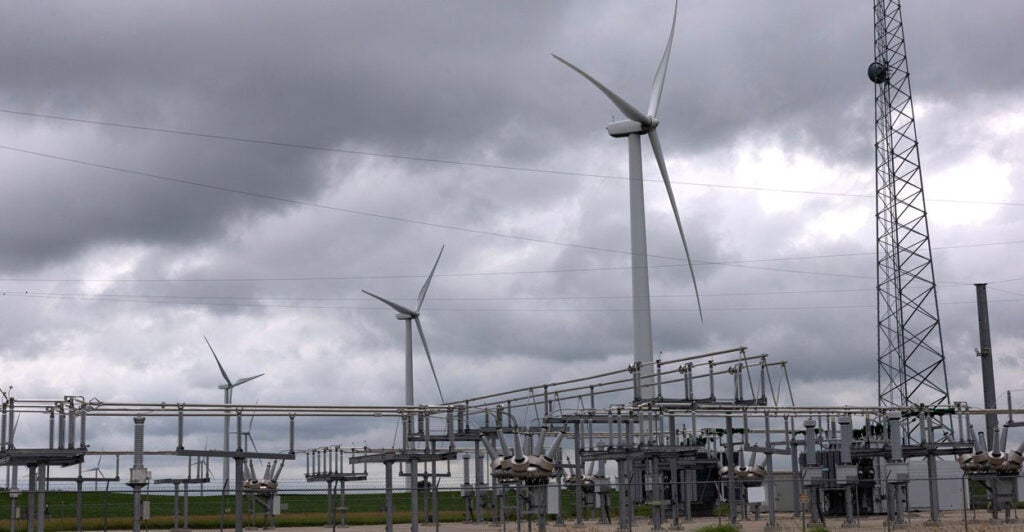 Large wind turbines dominate the skyline on a cloudy day in Iowa.