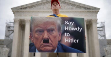 A man with a sign equating President Donald Trump to Adolf Hitler protests in a possible manifestation of Trump Derangement Syndrome at the Supreme Court