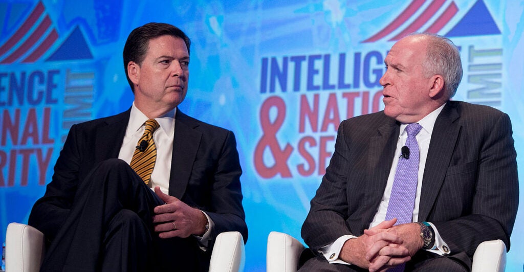 Then FBI Director James Comey (L) and CIA Director John Brennan speak seated side by side at an event in D.C.