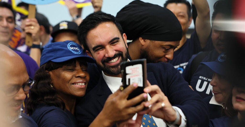 Zohran Mamdani takes a selfie with a black supporter, with two other black supporters alongside.