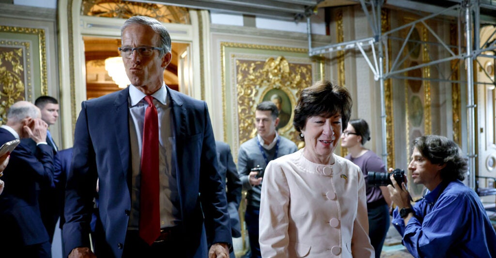 Sen. John Thune and Sen. Susan Collins walk together amid a crowd of people in the U.S. Capitol.