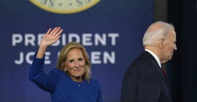 Joe Biden turns away as Jill Biden waves in front of sign reading "President Joe Biden."