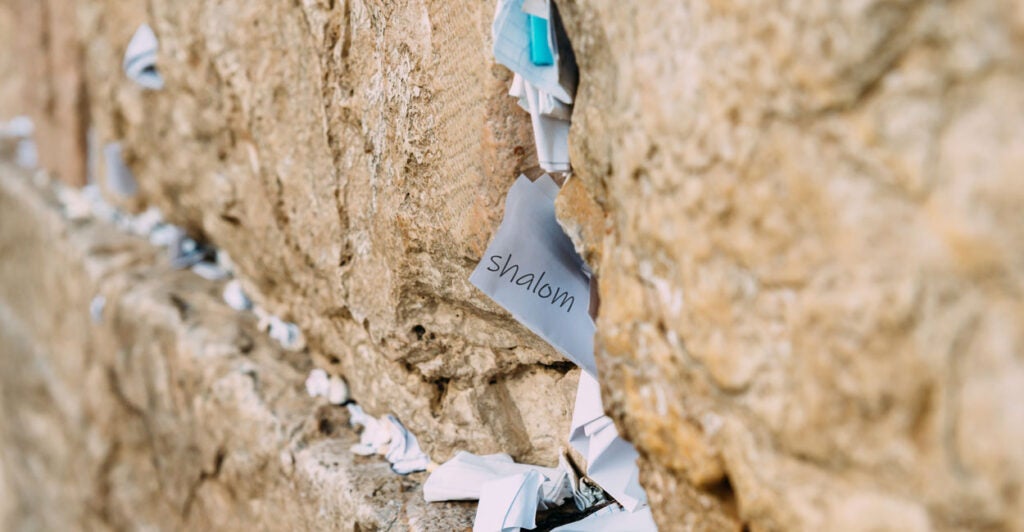 A note reading "Shalom"—Hebrew for "Peace"—sticks out of the Western Wall in Jerusalem, along with many other notes.