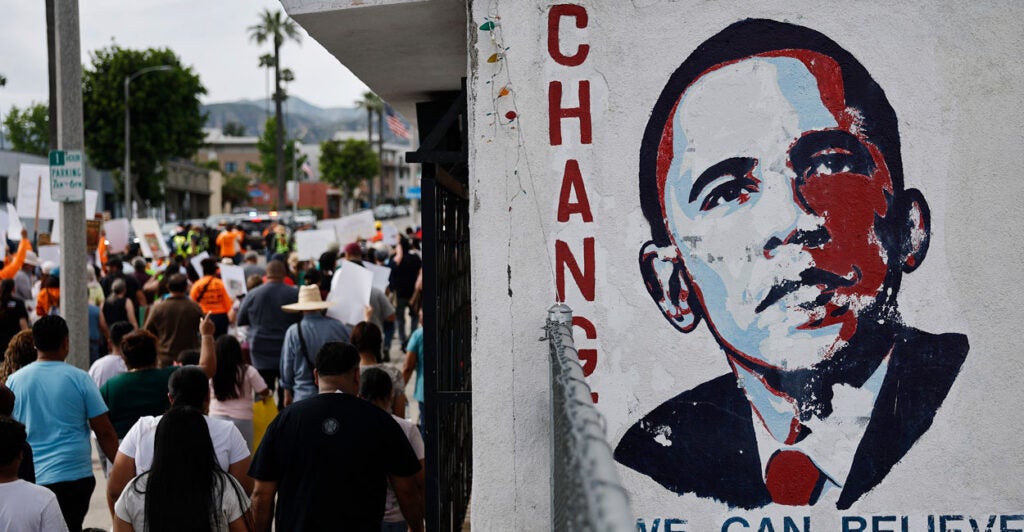 An Obama "Change" poster with his portrait hangs on a busy street.