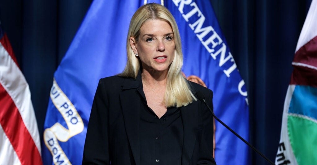 U.S. AG Pam Bondi speaks at an event with flags behind her.