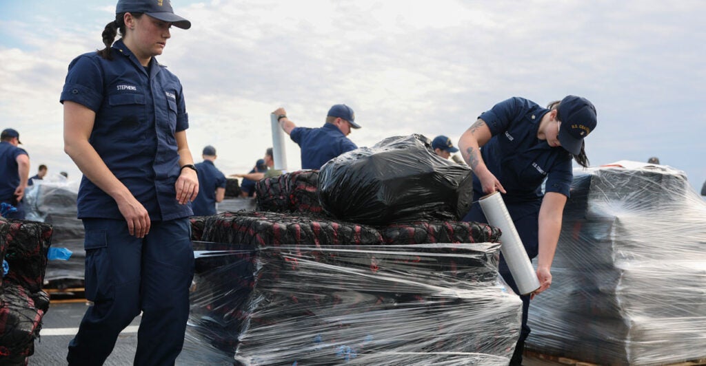 Coast Guard crew members offload cocaine and marijuana seized from smugglers.