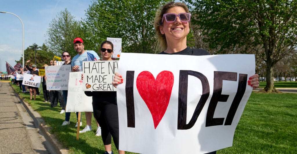 protesters along the street. The one in front is holding a sign that says I love DEI