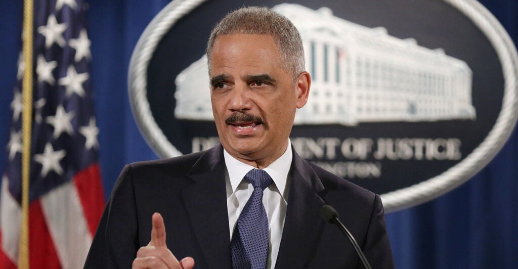 Eric Holder in front of a Justice Department sign