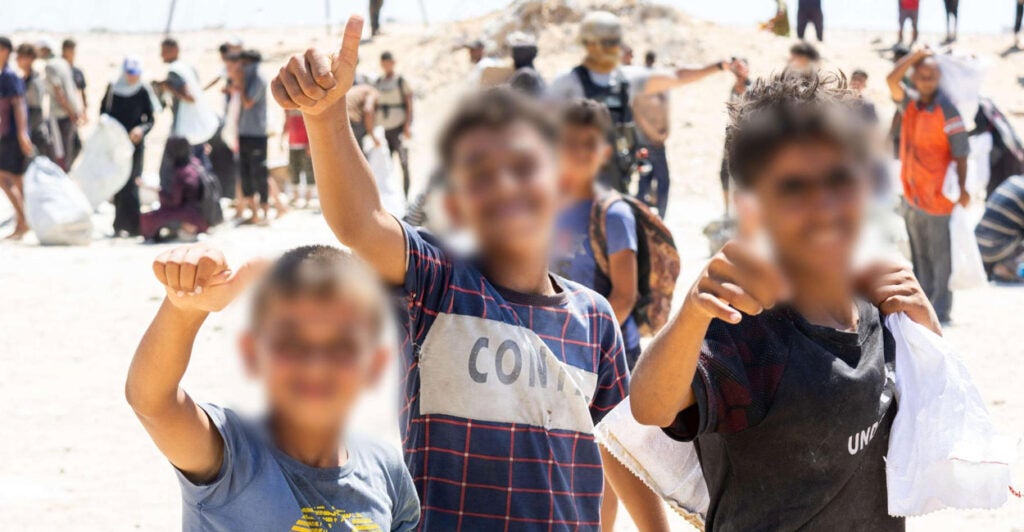 Children pose for a photo at a Gaza Humanitarian Foundation aid site in Gaza.