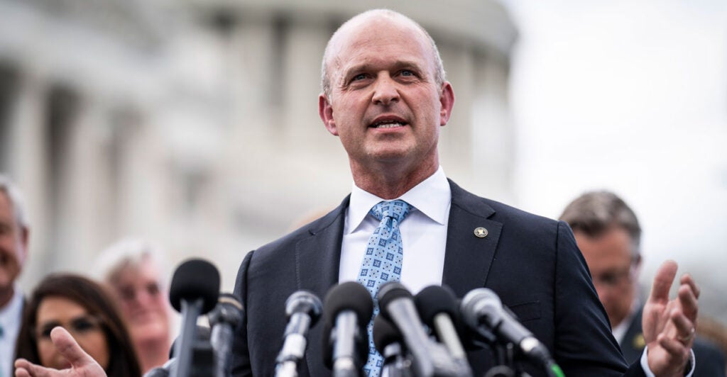 Heritage Action President Kevin Roberts speaks into a number of microphones outside the U.S. Capitol building, with a group of people behind him.