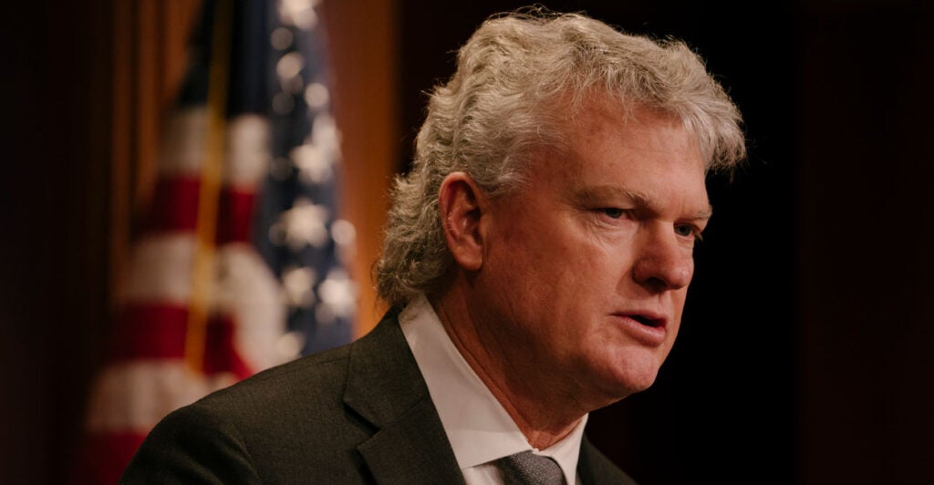 Georgia Rep. Mike Collins speaks in front of an American flag backdrop at the Capitol.
