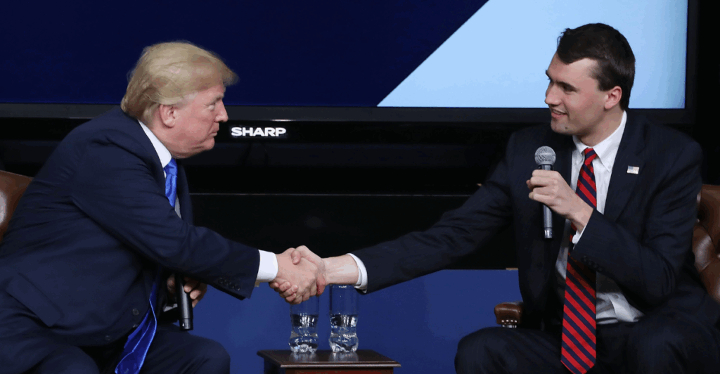 President Donald Trump, left, and Charlie Kirk, right, shake hands at a conference