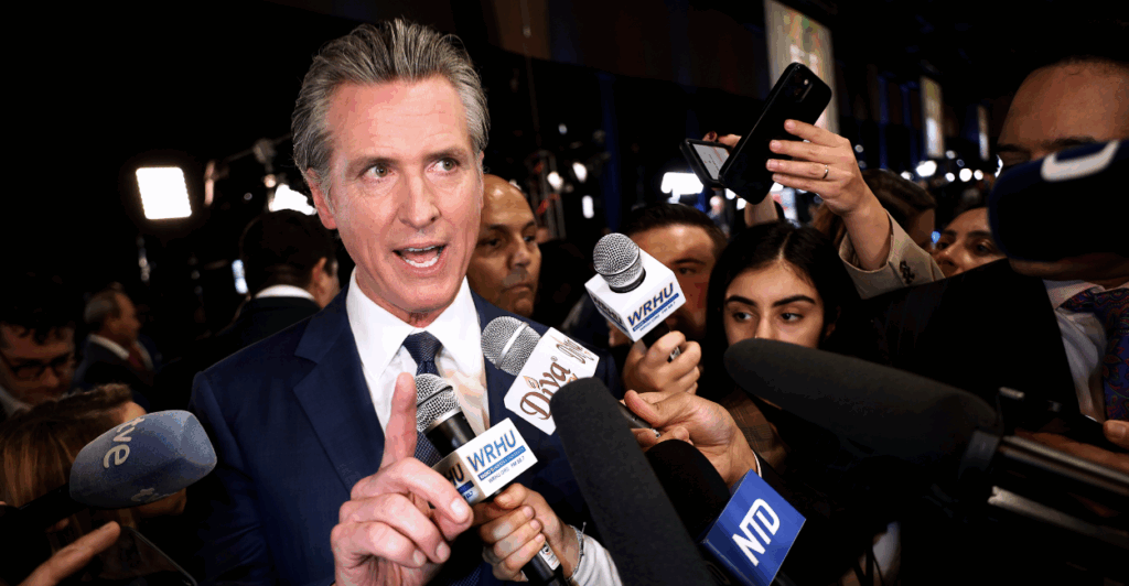 California Gov. Gavin Newsom points a finger while speaking to a group of reporters.