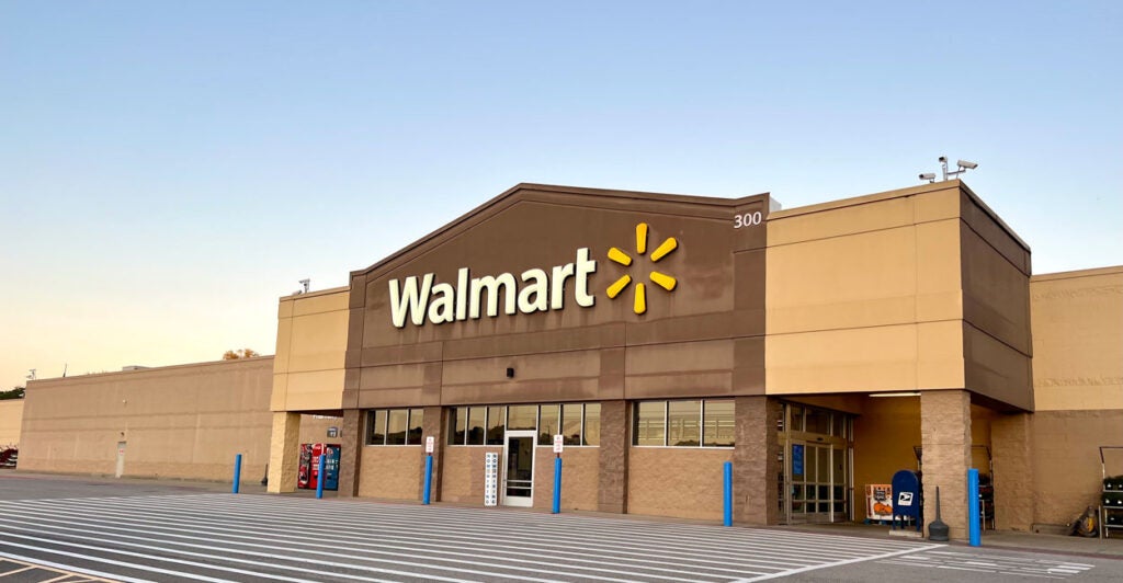 Photo shows the front of a Walmart with a light blue sky behind it.