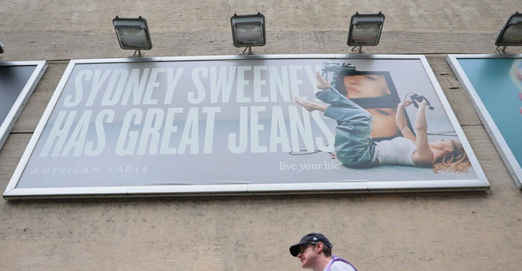 A man is walking by a billboard of actress Sydney Sweeney is seen outside of an American Eagle store.