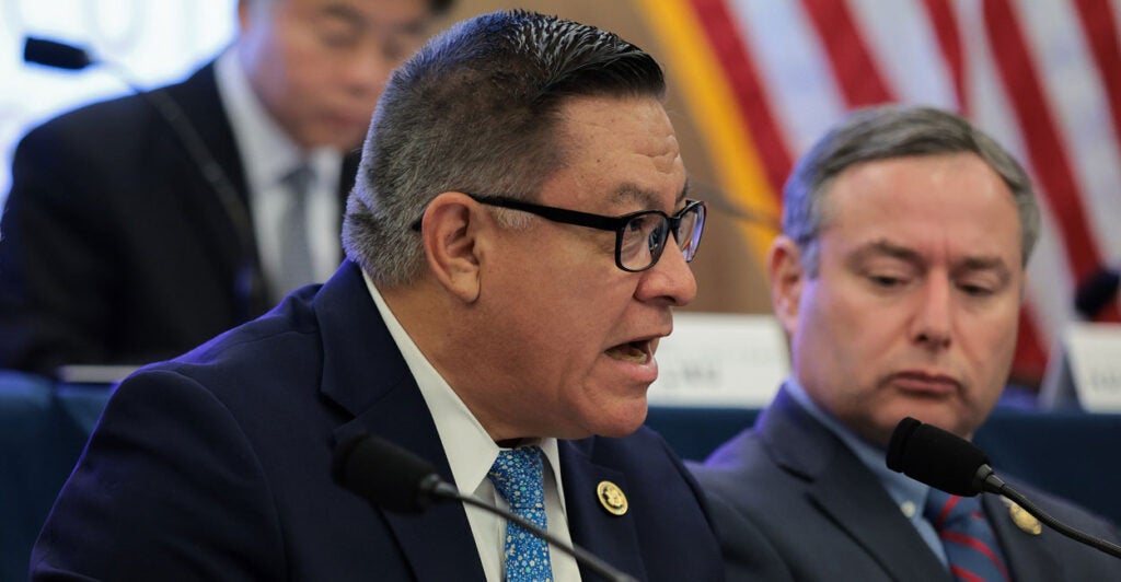 Salud Carbajal sits at a table and speaks to reporters during a press conference.