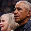 Barack Obama sits in the stands of an NBA game and looks ahead.