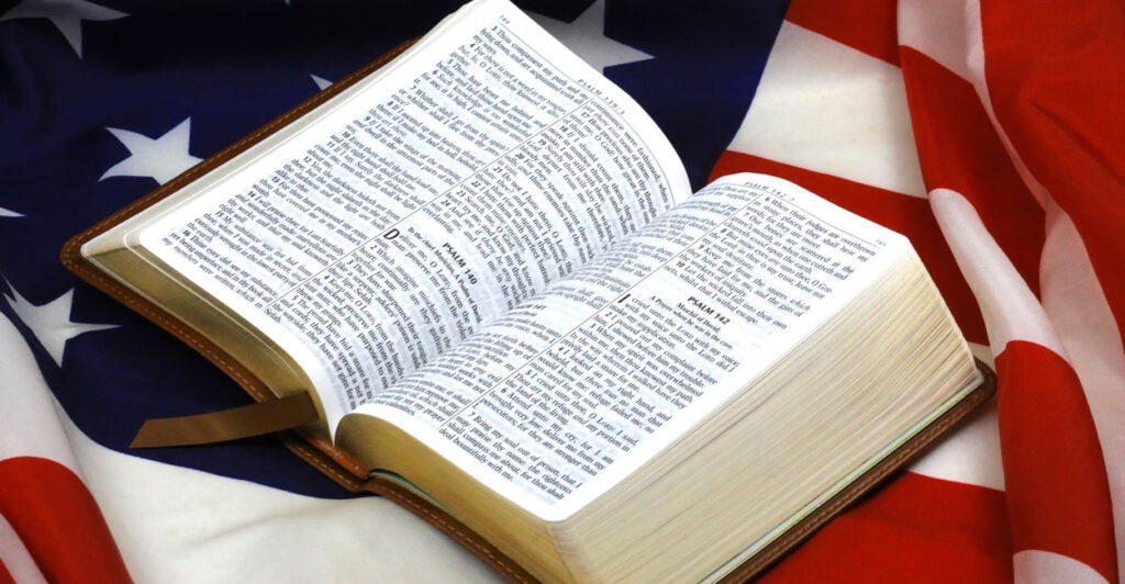 An opened Bible rests atop a U.S. flag