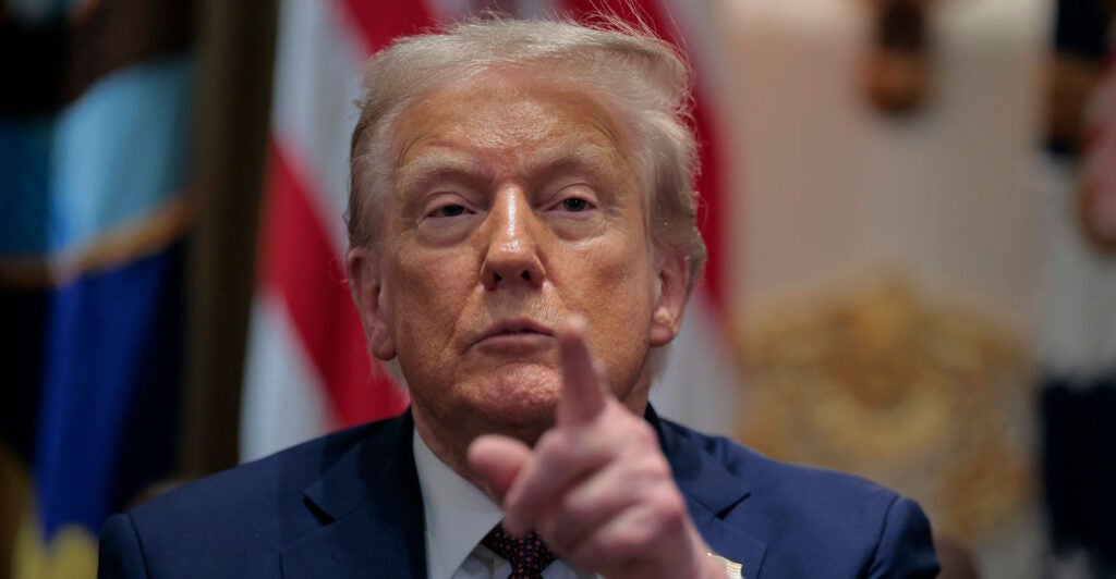 Donald Trump points with his left hand at a reporter during a press conference.