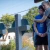 A woman hugs a child as they look upon two crosses marking the sight of a school shooting.