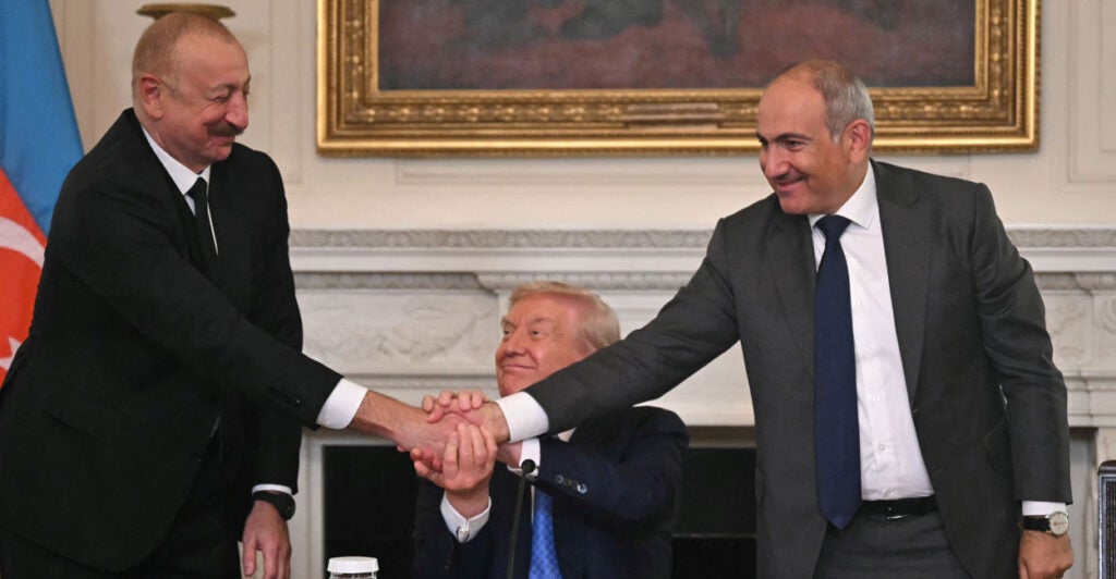 A beaming President Donald Trump (C), Azerbaijani President Ilham Aliyev (L) and Armenian Prime Minister Nikol Pashinyan shake hands after signing an agreement in the State Dining Room of the White House in Washington, DC, on August 8, 2025.