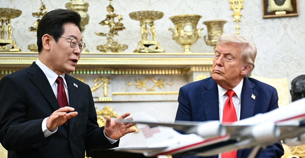 President Donald Trump listens as South Korean President Lee Jae Myung speaks during their meeting in the Oval Office. Both men are wearing dark suits.