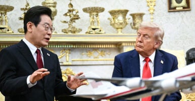 President Donald Trump listens as South Korean President Lee Jae Myung speaks during their meeting in the Oval Office. Both men are wearing dark suits.
