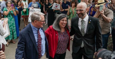 Three CDC officials who resigned after firing of CDC director lock arms as crowd of supporters look on.